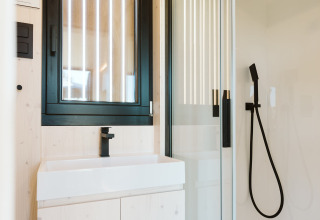 Modern compact badkamer in een tiny house bij Holiday park De Klepperstee, Nederland, met zwarte kranen.
