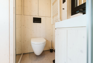 Baño moderno y compacto en la tiny house Backer en Holiday park De Klepperstee, Países Bajos, con paneles de madera.