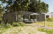 Lodge moderno en el parque vacacional De Klepperstee, Países Bajos, con terraza, madera y sombrilla.