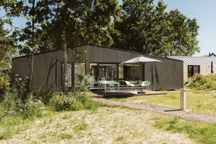 Lodge moderno en el parque vacacional De Klepperstee, Países Bajos, con terraza, madera y sombrilla.