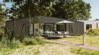 Lodge moderno en el parque vacacional De Klepperstee, Países Bajos, con terraza, madera y sombrilla.