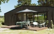 Moderne Terrasse mit Gartenmöbeln und Sonnenschirm vor der Eden Lodge im Ferienpark De Klepperstee, Niederlande.