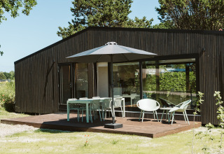 Terrazza moderna con tavolo, sedie e ombrellone presso la lodge Eden, Holiday park De Klepperstee, Paesi Bassi.