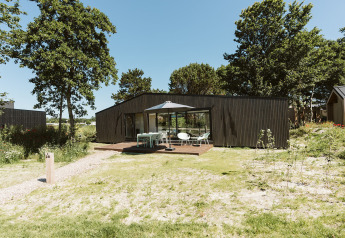 Moderne Eden-lodge op vakantiepark De Klepperstee in Nederland, met terras en tuinmeubilair.