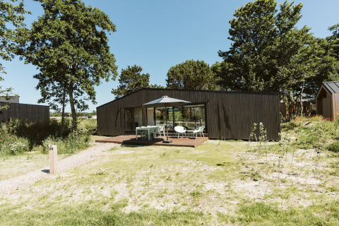 Moderne Eden-lodge op vakantiepark De Klepperstee in Nederland, met terras en buitenmeubels.