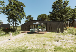 Moderne Eden-lodge op vakantiepark De Klepperstee in Nederland, met terras en buitenmeubels.