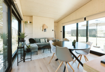 Interno moderno di lodge presso Eden nel Holiday park De Klepperstee, Paesi Bassi, con ampie finestre luminose.