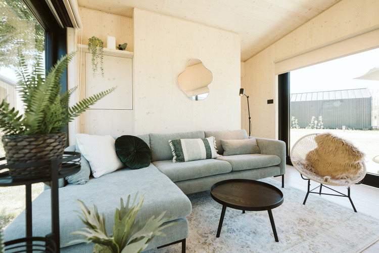 Helles, modernes Wohnzimmer in der Eden-Lodge im Holiday Park De Klepperstee mit Pflanzen und Sofa.
