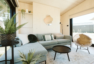 Lichte, moderne woonkamer in Eden-lodge van Holiday park De Klepperstee, met planten en hoekbank.