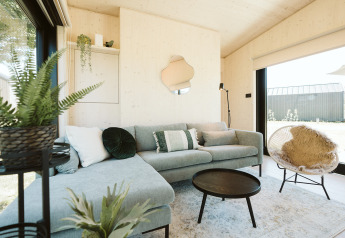 Lichte, moderne woonkamer in Eden-lodge van Holiday park De Klepperstee, met planten en hoekbank.