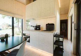 Moderne køkken- og spiseplads med lyse træpaneler på Eden lodge, Holiday park De Klepperstee, Holland.