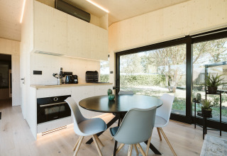 Zona moderna de comedor y cocina en la cabaña Eden del Holiday park De Klepperstee con grandes ventanales y vistas.