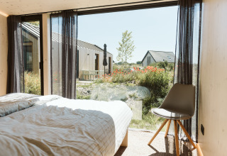 Uitzicht vanuit slaapkamer van Eden lodge in Holiday park De Klepperstee met grote ramen en tuinen.