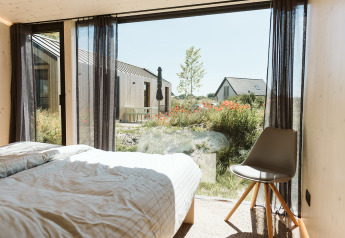 Vue depuis la chambre à Eden lodge au Holiday park De Klepperstee, avec grandes fenêtres et jardins fleuris.