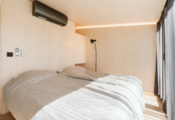 Slaapkamer in Eden lodge bij Holiday park De Klepperstee, Nederland, met tweepersoonsbed en zonlicht.