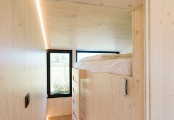 Habitación luminosa y moderna con cama elevada y grandes ventanas en Eden lodge, Holiday park De Klepperstee, Países Bajos.