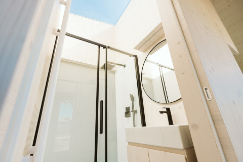 Modern bathroom with glass shower, round mirror and skylight at Eden lodge, Holiday park De Klepperstee.