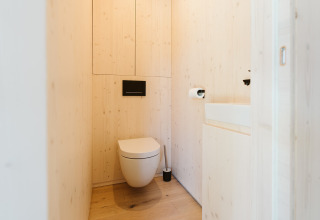 Bagno moderno rivestito in legno con wc sospeso e lavabo a Eden, Holiday park De Klepperstee, Paesi Bassi.