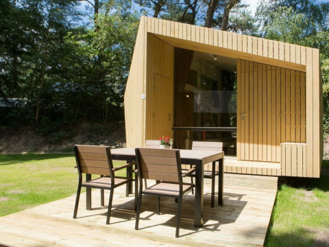 Moderne tiny house Trek-in i Beerze Bulten, Holland, med træterrasse og havemøbler i solskin.