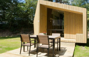 Casa pequeña moderna Trek-in en Beerze Bulten, Países Bajos, con terraza de madera y muebles de exterior.