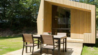 Moderne tiny house Trek-in bij Beerze Bulten, Nederland, met houten terras en tuinset buiten.