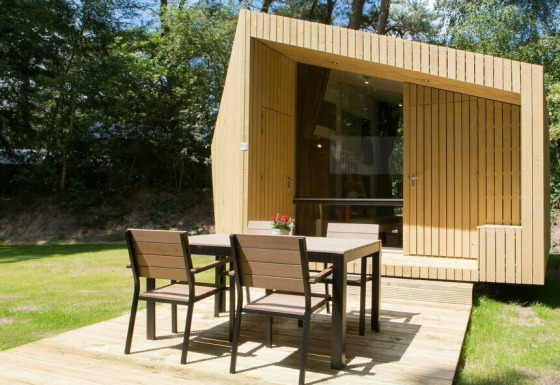 Tiny house moderna Trek-in a Beerze Bulten, Paesi Bassi, con patio in legno e mobili da esterno.