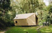 Kleine Trek-in blokhut bij Beerze Bulten in Nederland, omgeven door bos en met tuinmeubilair buiten.