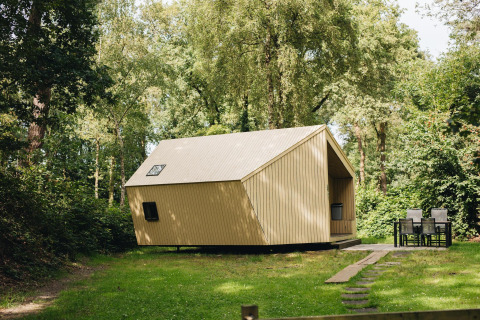 Pequeña casa de madera Trek-in en Beerze Bulten, Países Bajos, rodeada de bosque y zona exterior.