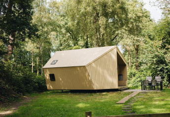 Tiny house Trek-in en bois à Beerze Bulten, Pays-Bas, entourée de forêt et espace extérieur aménagé.