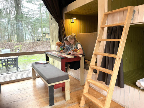 Due bambini giocano a un tavolo dentro una tiny house Trek-in a Beerze Bulten, Paesi Bassi.
