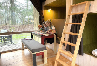 Due bambini giocano a un tavolo dentro una tiny house Trek-in a Beerze Bulten, Paesi Bassi.