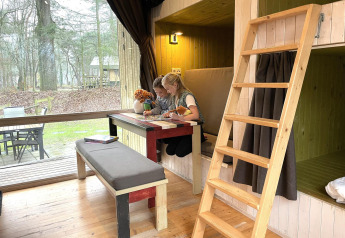 Due bambini giocano a un tavolo dentro una tiny house Trek-in a Beerze Bulten, Paesi Bassi.