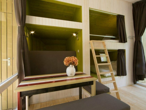 Pequeña casa Trek-in moderna en Beerze Bulten, Países Bajos, con literas, mesa y escalera de madera.
