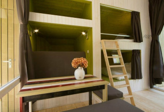 Moderne trek-in tiny house på Beerze Bulten i Holland med sovepladser, spisebord og trappe.