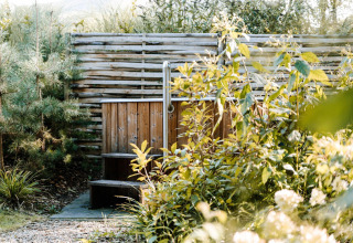 Jacuzzi de madera exterior entre plantas en Luxury Family Water Lodge + hot tub en Soof Retreats, Países Bajos.