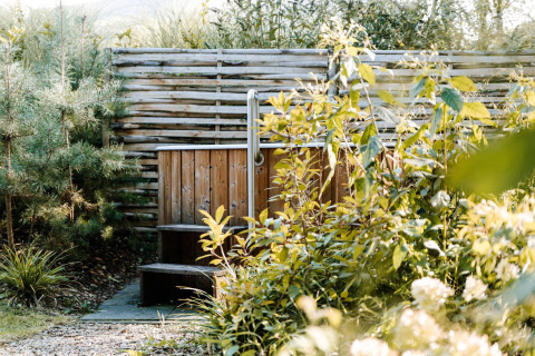 Outdoor wooden hot tub surrounded by lush greenery at Luxury Family Water Lodge, Soof Retreats, Netherlands.