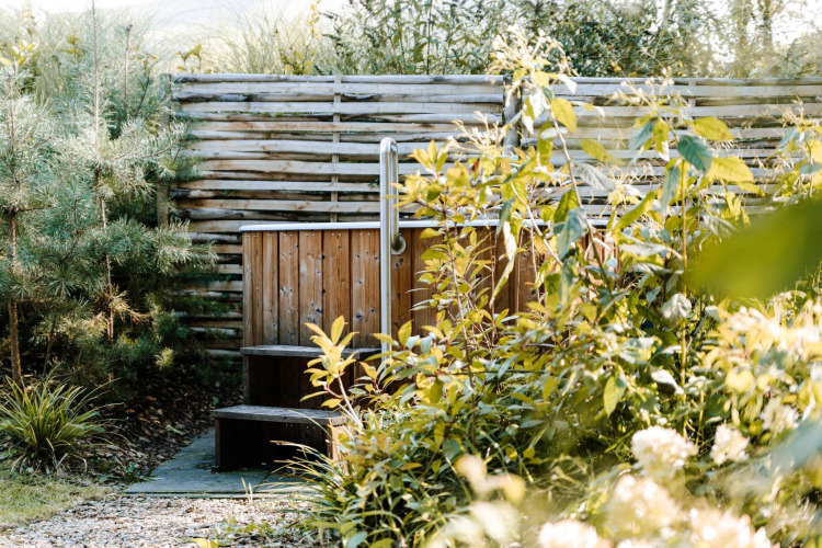 Outdoor wooden hot tub surrounded by lush greenery at Luxury Family Water Lodge, Soof Retreats, Netherlands.