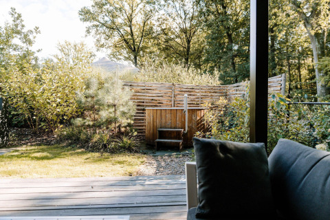 Vista desde una terraza con sofá, cerca de madera y jacuzzi privado en Soof Retreats, Países Bajos.