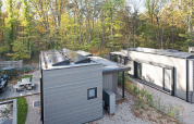 Moderne lodge in het bos met zonnepanelen op het dak, zitgedeelte en omringd door herfstbomen.