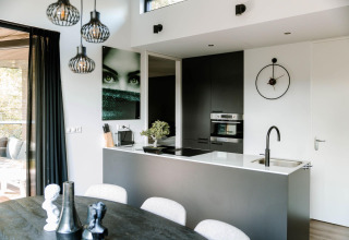 Moderne lodge keuken met zwart-wit inrichting, kunst aan de muur, klok en groot raam met natuurlijk licht.