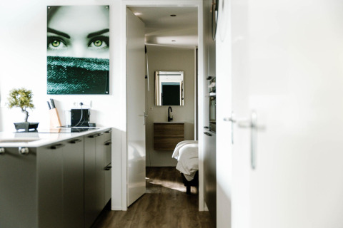 Modern lodge kitchen with sleek design, wood flooring, wall art, and a view through to the bedroom area.