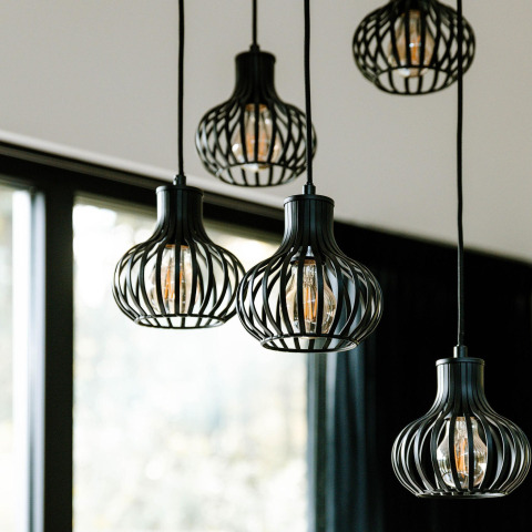 Moderne hanglampen met zwart metalen kader in een lodge, met grote ramen en veel daglicht.