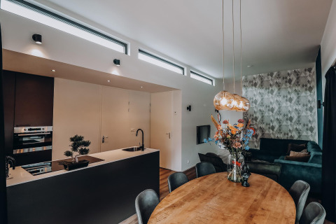 Moderne lodge met open keuken, ronde houten tafel met bloemen en een gezellige zithoek met sofa.