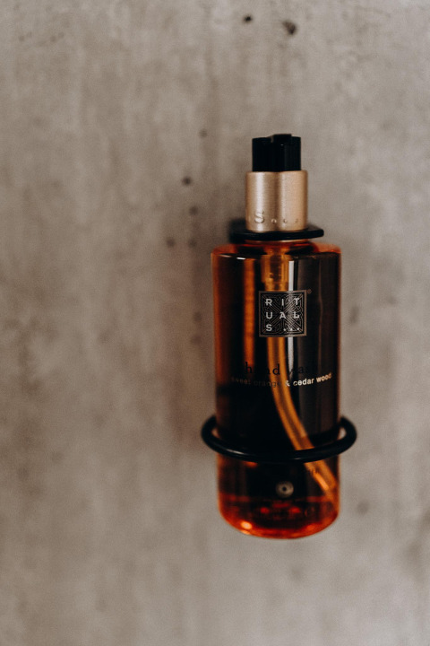 Amberkleurige Rituals dispenser aan de muur, gefotografeerd in een lodge, met zichtbare tekst op het flesje.