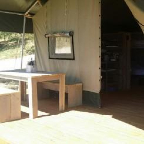 Vue intérieure et extérieure de la tente Safari à Agricamping Romita en Italie, avec table et banc en bois.