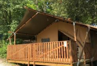 Tienda safari con instalaciones sanitarias y terraza de madera en Camping Mar y Sierra, rodeada de árboles.
