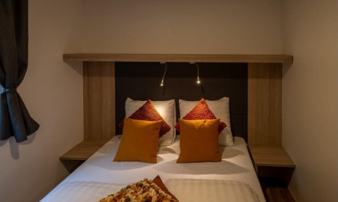 Acogedor dormitorio en Heiberg cottage en Hoge Kempen, Bélgica, con cama doble, cojines y luces de lectura.