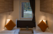 Interieur van Heiberg cottage in Hoge Kempen, België, met twee bedden, kussens en zicht op het bos.