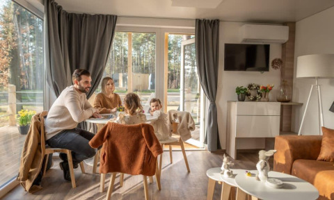 Gezin eet samen in het knusse Heiberg cottage in Hoge Kempen, België, met zicht op de natuur.