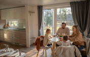 Famille prenant un repas dans le chalet Heiberg à Hoge Kempen, Belgique, intérieur chaleureux et moderne.